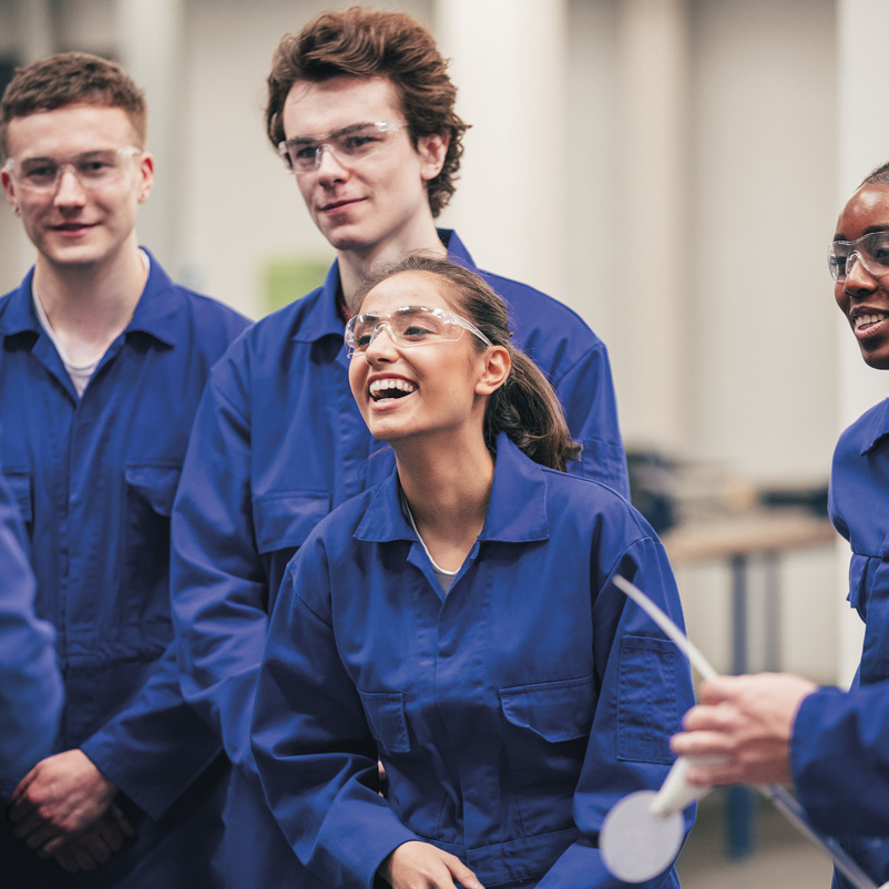 group of young employees in boiler suits laughing and smiling