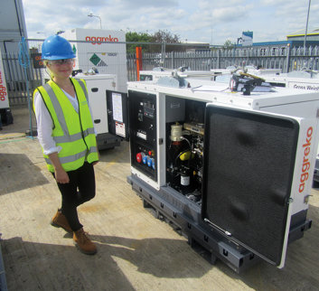 young female in high vis waistcoat stood next to an aggreko piece of equipment